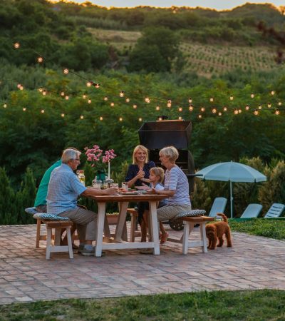 Three generation family having a garden party in the summer. They are sitting at the dining table in the backyard and having dinner