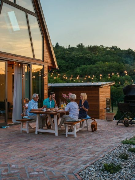 Three generation family having a garden party in the summer. They are sitting at the dining table in the backyard and having dinner